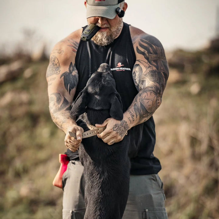 Man with tattoos holding a deer in a field